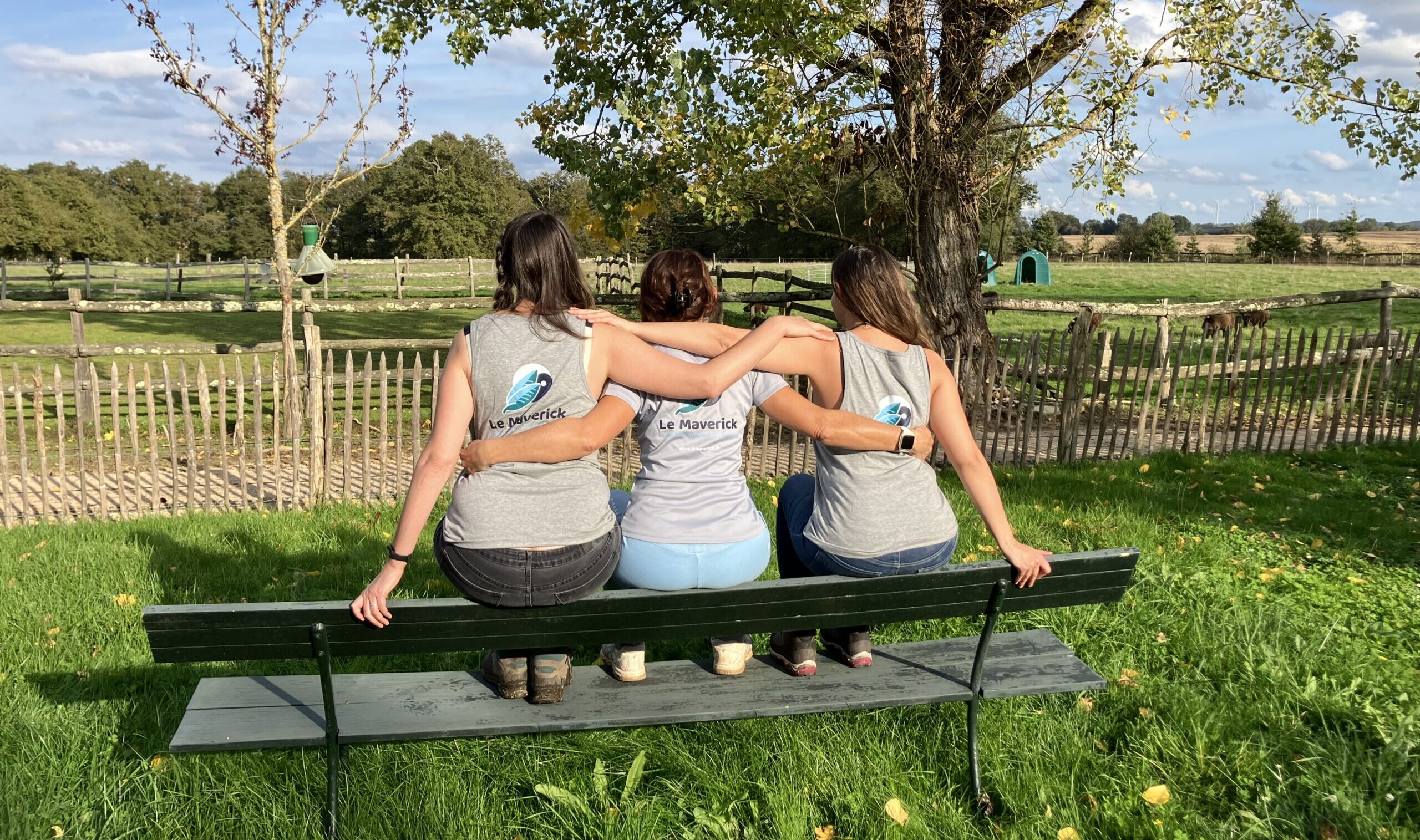 Three women facing away with arms around each other looking over countryside France